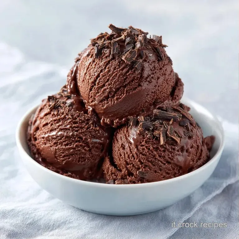 Coppa di vetro con dessert marrone lucido, colata di cioccolato fondente vellutata e una scaglia di cacao croccante sopra.
